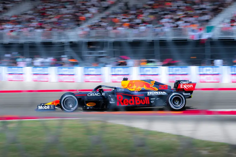 Formula 1 car passing packed grandstands, panning shot